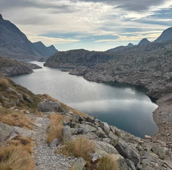 Dlouhé horské jezero v kamenité krajině pod zataženou oblohou